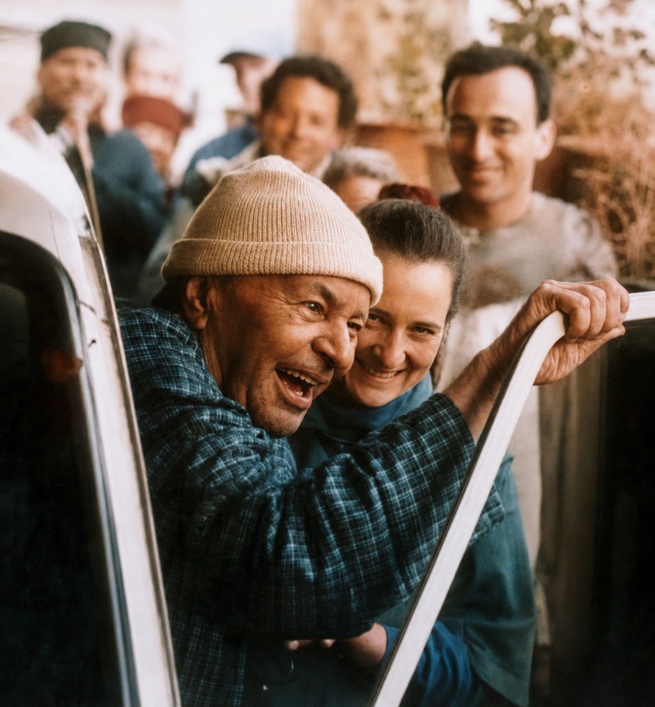 Papaji laughing with devotees beside a car